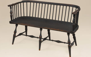 Historical Low-Back Windsor Settee in black over red finish with classic Windsor design.