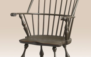 Historical Plymouth Sack-Back Windsor Armchair with carved knuckles, shaped seat, and a primitive antique finish.