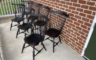 Set of 7 Historical Fan Back Windsor Side Chairs with carved ears and shaped seats in antique black over red crackle finish, American made.