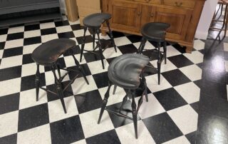 Set of 4 Historical Saddle Seat Kitchen Stools with 25in seat height, antique black over red crackle finish, ideal for 36in counter height, American made.