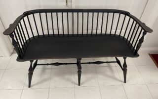 Historical Low Back Windsor Settee with Antique Black over Red Crackle Finish. Ideal for hallways, foyers, or living rooms.
