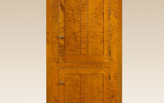 Blind Door Corner Cabinet in country style with scalloped apron and flat panels, crafted in tiger maple wood, cherry wood, or painted finishes.