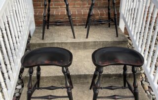 Set of Four Backless Counter Stools with Windsor style turned legs, shaped seats, and antique black over red crackle finish, made in the USA.