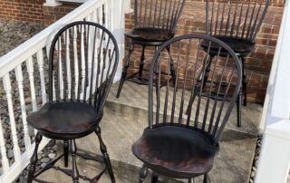 Set of Four Swivel Windsor Stools with bow backs, turned legs, and antique black over red crackle finish, made in the USA.