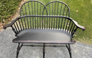 Double Sack Back Windsor Settee featuring turned legs, carved knuckles, and antique black over red crackle finish, handcrafted in the USA.