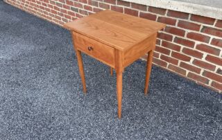 Natural Finish Cherry Stand with dovetailed drawer, simple turned legs, and walnut drawer pull, crafted in the USA for versatile decor.