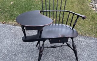 Fan Back Windsor Writing Armchair with carved knuckles, carved ears, and two drawers, finished in antique black over red crackle, made in the USA.