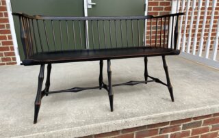 An American-made Historical Low Back Windsor Settee with bamboo-style turned legs and arm supports.