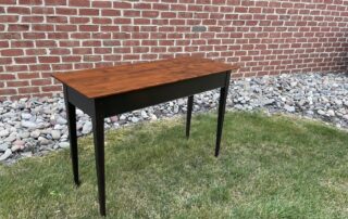 Pennsylvania Made Hall Table with a hand-planed and distressed cherry wood top, featuring tapered legs mortised, tenoned, and pinned for durability. Finished in antique black over red for a striking contrast and rustic charm.