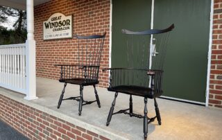 Philadelphia Comb Back Windsor Armchairs with a comb back design, intricately carved knuckles, and turned legs for exceptional stability. Finished in antique black over red crackle, adding vintage charm to any room.