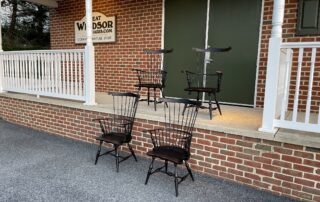Set of 4 Fan Back Windsor Armchairs with intricately carved ears and knuckles, turned legs, and a vintage antique black over red crackle finish. Perfect for dining or as accent chairs, blending traditional craftsmanship with bold design.