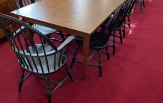 A set of 8 American-made Windsor chairs, including 2 Jefferson Windsor Armchairs and 6 Jefferson Windsor Side Chairs. Each chair features an antique black over red crackle painted finish, adding rustic charm and vintage appeal. This set is perfect for a dining room or kitchen table, offering both style and durability.