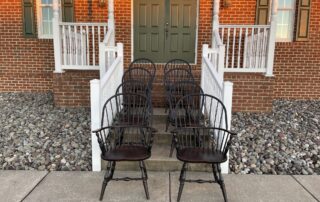Set of Eight Windsor Chairs with 2 Sack Back Armchairs and 6 Bow Back Side Chairs, featuring turned legs and antique black over red finish.