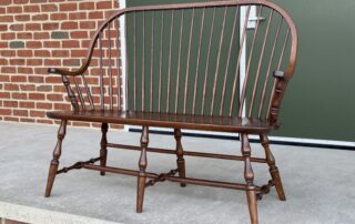 Oak Pennsylvania Made Windsor Settee with a continuous arm design and turned legs, finished in Pennsylvania Walnut Stain Finish.