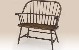Oak Small Windsor Settee with a sack back design, turned legs, and a Pennsylvania Walnut finish. Crafted in Pennsylvania.