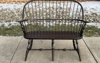 Pennsylvania Made Sack Back Settee with a Windsor-style design, turned legs, and antique black over red finish. Classic crafted seating.