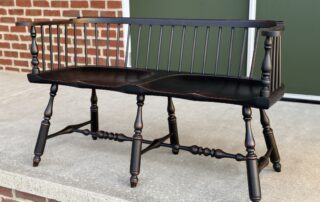 Low Back Windsor Settee with shaped seat and antique black over red finish.