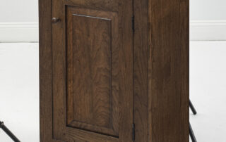 Small cherry wood cabinet with raised panel front and period walnut finish.