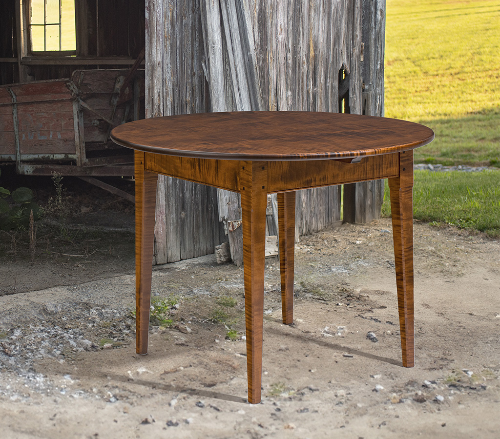 Round farmhouse table with tiger maple top and square tapered legs, ideal for kitchen or dining room use.